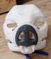 White bat mask with a dark gray nose on a wooden surface