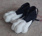 Black shoes with white feline or cat paw shaped 3D printed covers on a textured surface