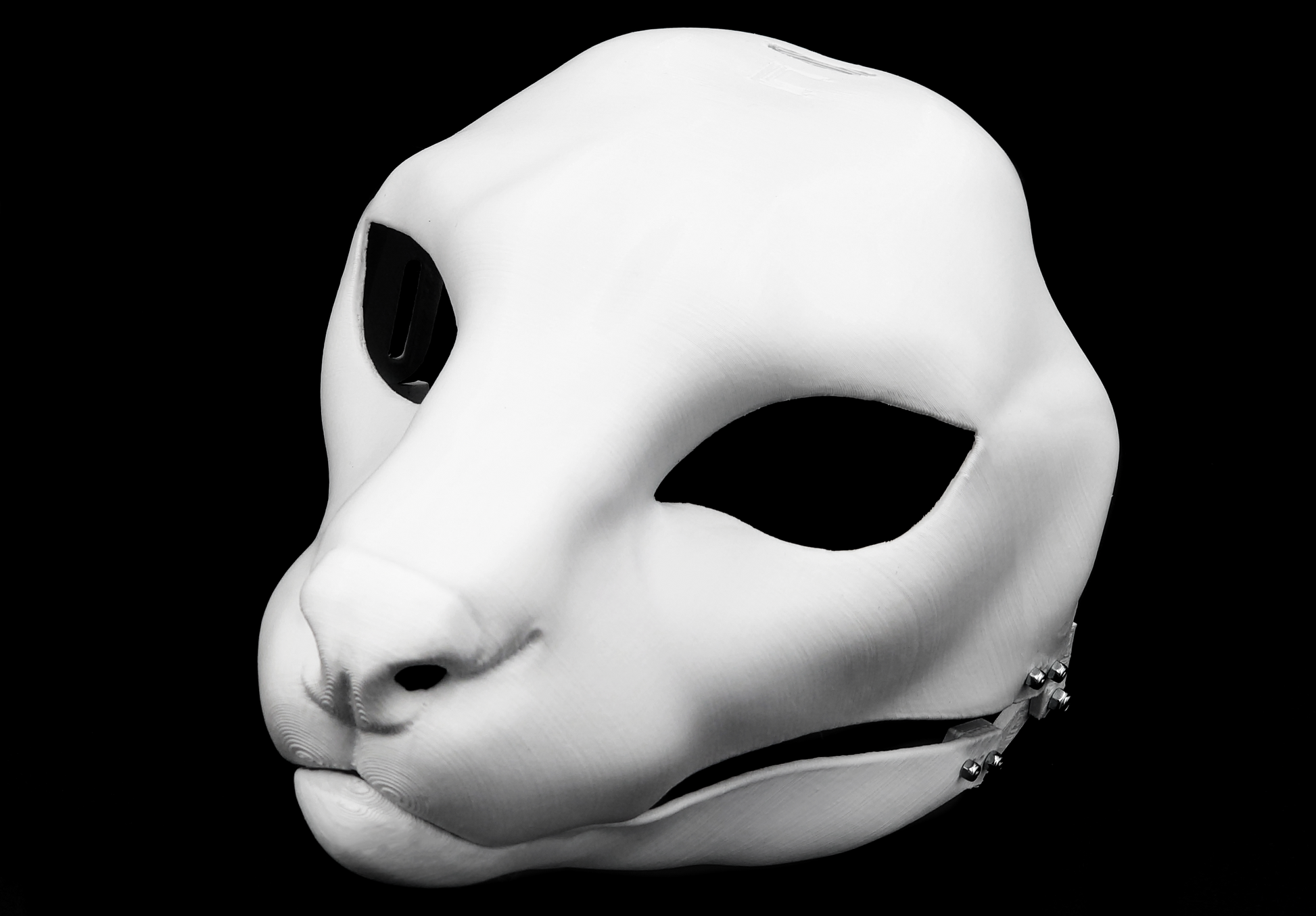 Photo showing a white, plastic 3D printed serval fursuit head base complete with metal hardware at a 3/4 angle against a black background.