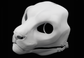 Photo showing a white, plastic 3D printed snow leopard fursuit head base complete with metal hardware at a 3/4 angle against a black background.